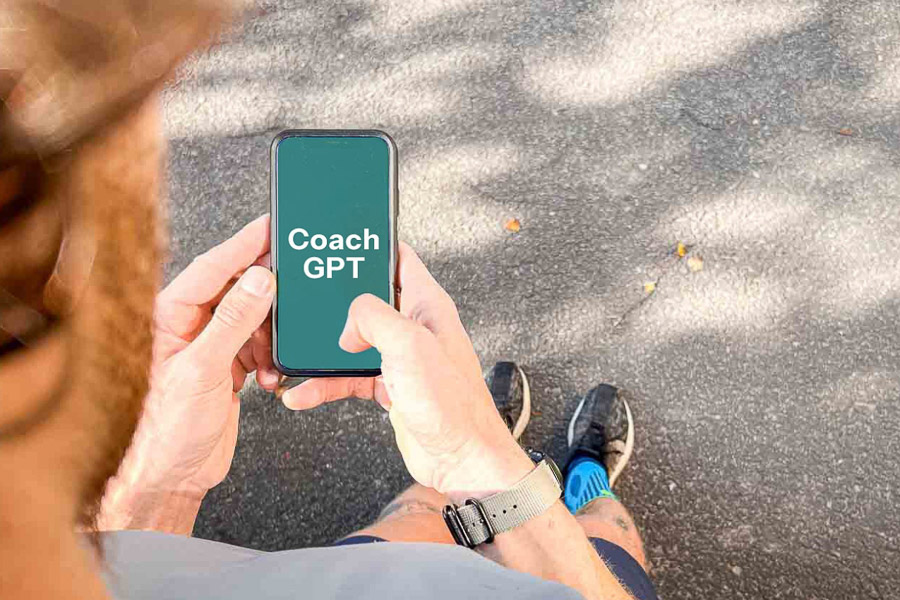 Ein Läufer hält ein Smartphone in der Hand, auf dem „Coach GPT“ angezeigt wird. Die Szene zeigt die Nutzung von KI-Technologie zur Unterstützung beim Lauftraining.