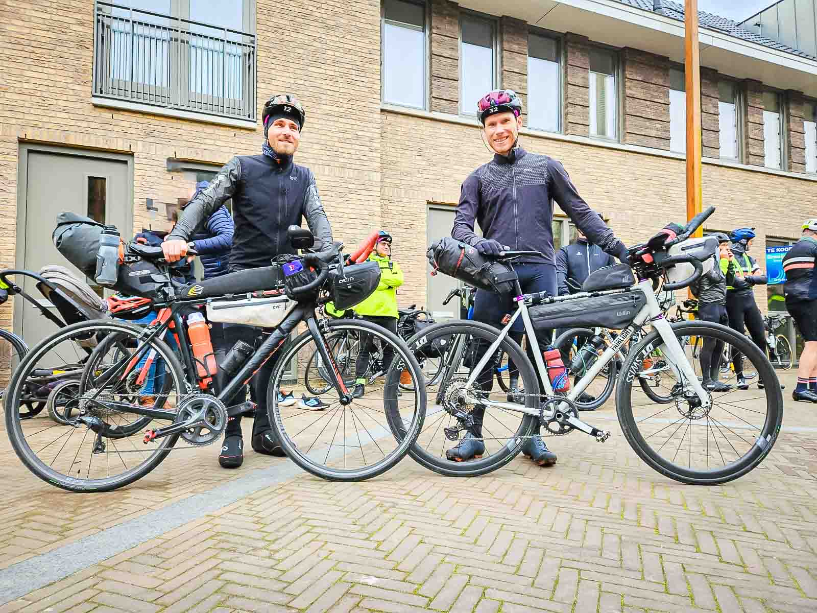 Zwei Teilnehmer am utra cycling Event Race around the Netherlands stehen am Start und lachen in die Kamera
