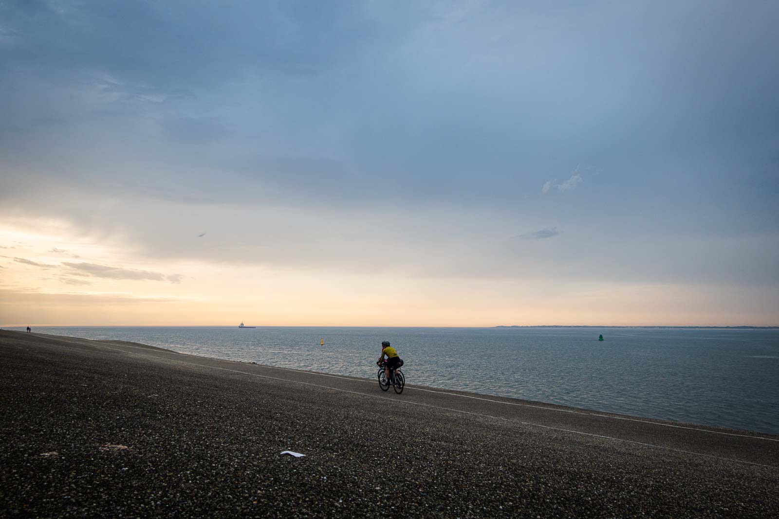 Zwei Teilnehmer des Race around the Netherlands fahren mit ihren Rädern der Abendsonne entgegen.