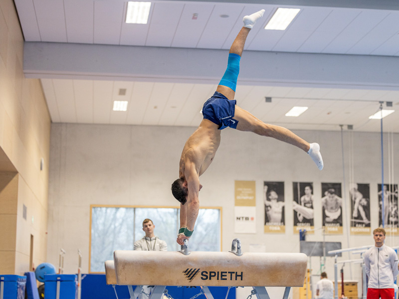 Andreas Toba in einer Sporthalle macht einen Handstand auf dem Pferd und trägt dabei eine Knie-Bandage.