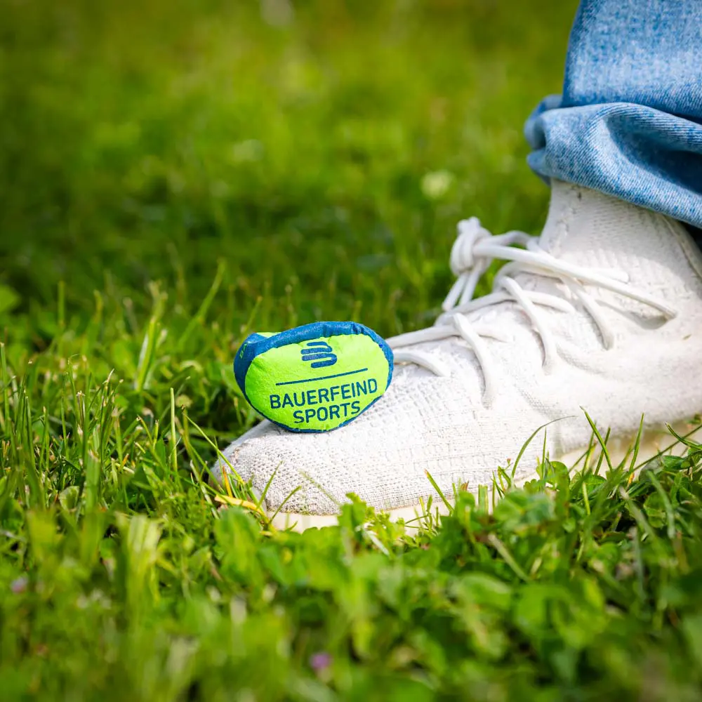 Kleiner Bauerfeind Sports Ball auf Gras, platziert neben einem weißen Schuh.