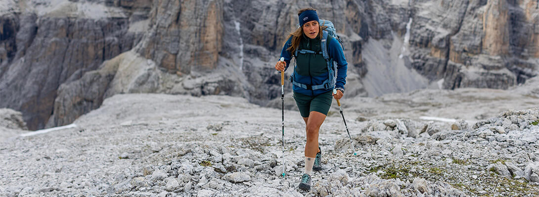 Frau beim Bergwandern auf felsigem Gelände in den Alpen die eine Wander Knöcheöbandage trägt